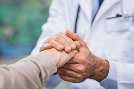 Doctor comforting patient by holding hand